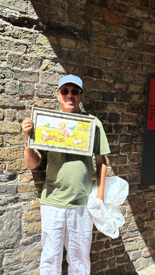 Jai Agarwal holding a small framed painting found at a market in Bruges