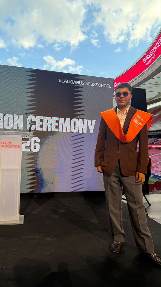 भूरे ब्लेज़र और नारंगी स्टोल में जय अग्रवाल, LaLiga Business School के दीक्षांत समारोह के बैकड्रॉप के सामने